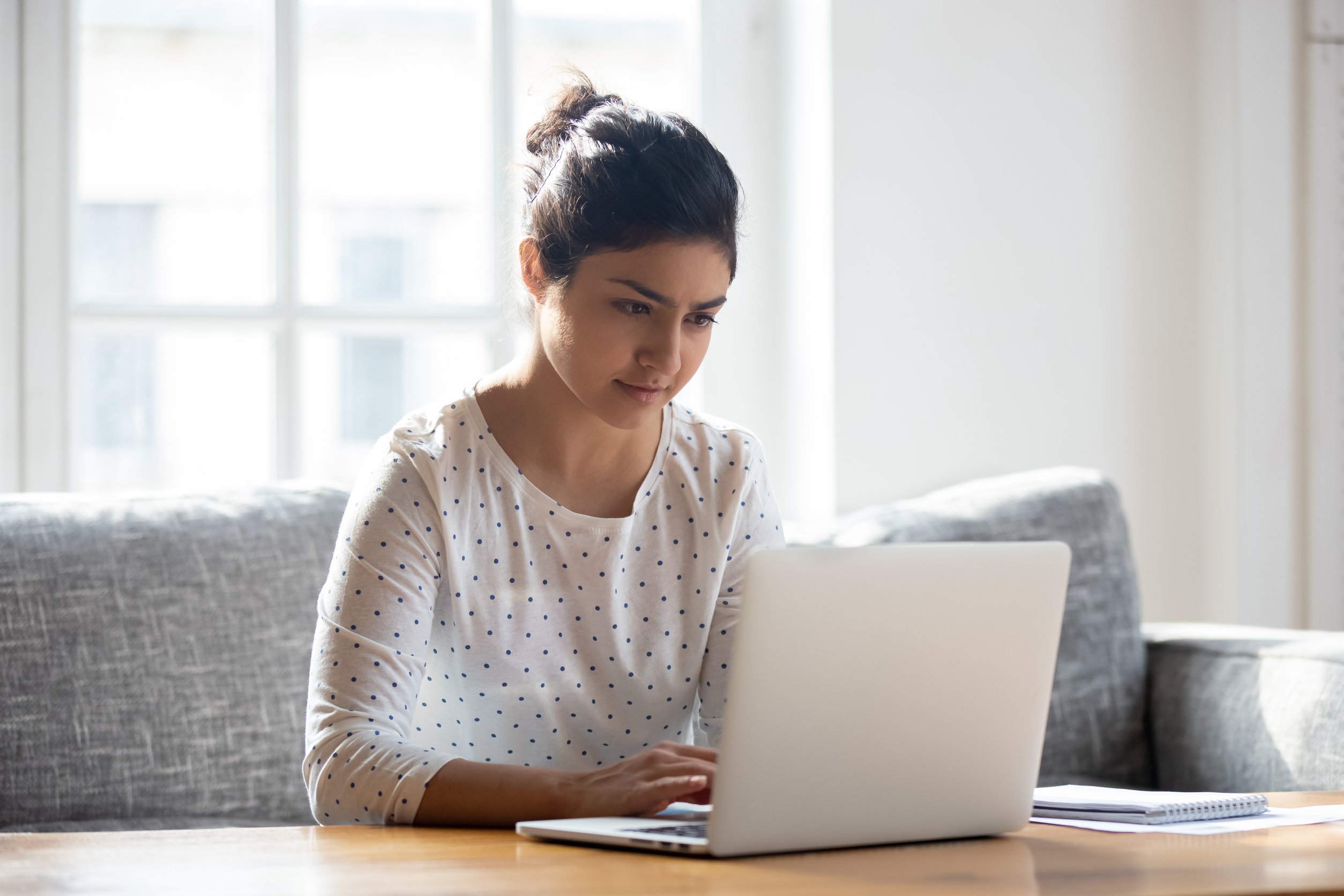 Image is of a women sitting down browsing on her laptop. 